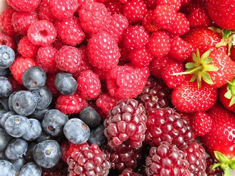 Fotografía de postres variados elaborados con frambuesas y frutos rojos como decoración principal
