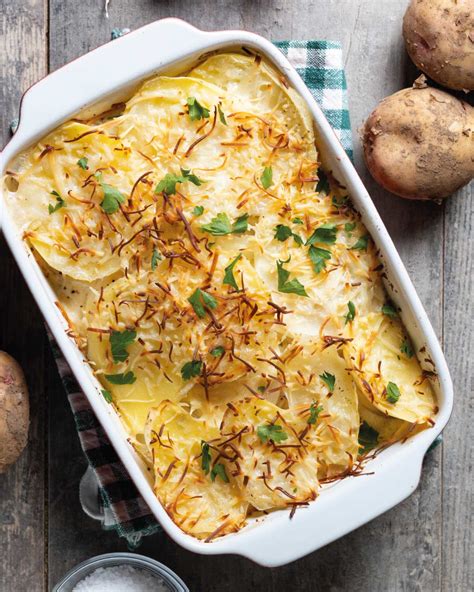 Capas de papas, cebolla, crema y queso en una fuente para horno