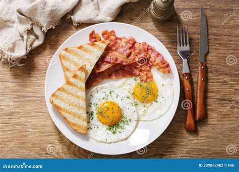 Plato de desayuno anglosajón con bacon frito, huevos y tostadas