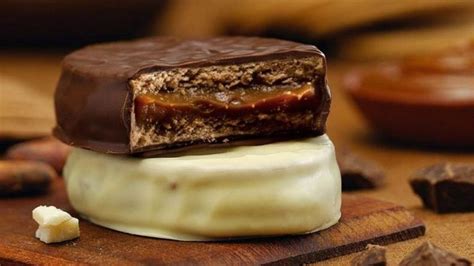 Primer plano de un alfajor chileno partido por la mitad, mostrando el relleno y la textura de las galletas.