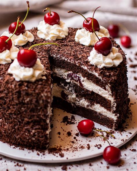 Fotografía de una Tarta Selva Negra clásica con virutas de chocolate y cerezas frescas.