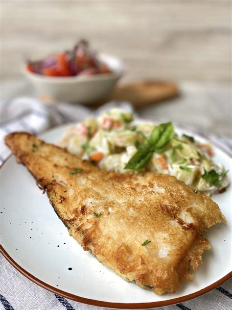 Plato de merluza frita clásica, servida junto a una fresca ensalada chilena.