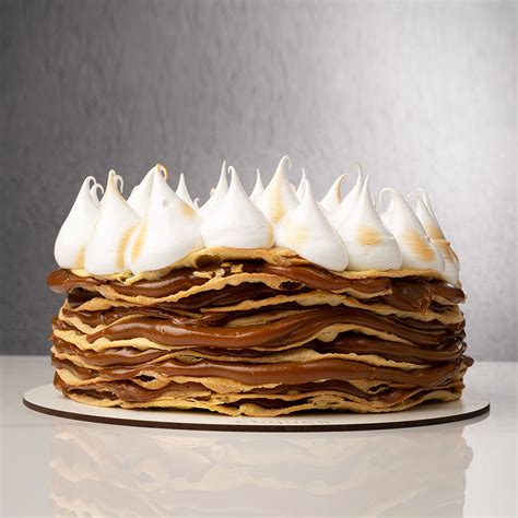 Ilustración de una Torta Rogel terminada, mostrando las capas de dulce de leche y el merengue decorativo.