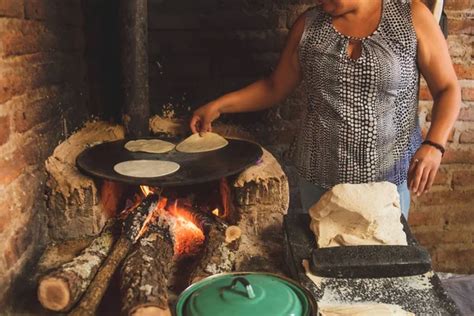 ilustración de una mujer indígena preparando tortillas en un comal tradicional