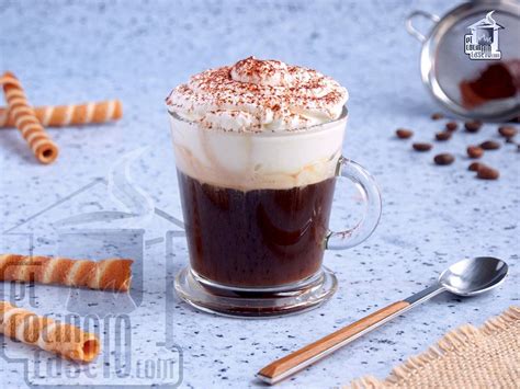 Imagen de un café vienés con su distintiva capa de nata montada y un toque de canela sobre una mesa elegante.