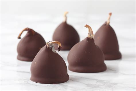 Foto de bombones de higo con chocolate, decorados con motivos románticos, junto a una copa de vino