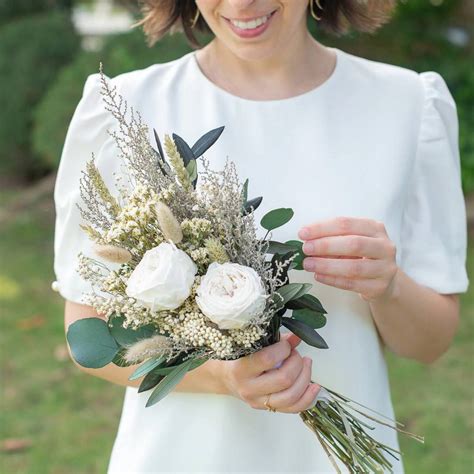 Un ramo de novia con rosas blancas y eucalipto, simbolizando pureza y comienzo.