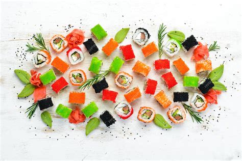 Platos de cerámica y madera con sushi de colores vibrantes sobre una mesa decorada