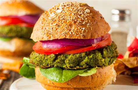 Fotografía de una hamburguesa vegana gourmet servida en un plato con guarnición de verduras frescas
