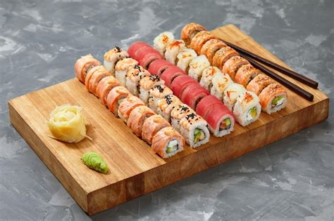 Fotografía profesional de una tabla variada de sushi con diferentes tipos de rolls, gyozas y salsas.