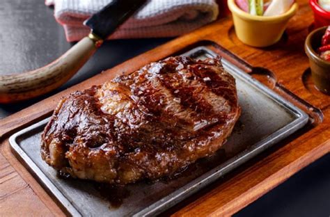 Fotografía profesional de un bife de chorizo a la cacerola servido con verduras cocidas.
