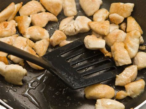 Pechuga de pollo siendo salteada en una sartén con ajo