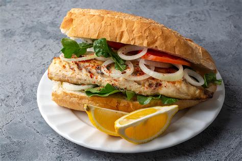 Una fotografía de un sándwich de pescado frito relleno con cebolla morada y ají verde