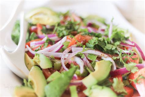 Plato servido de ensalada de cebolla morada y aguacate, decorado con perejil.