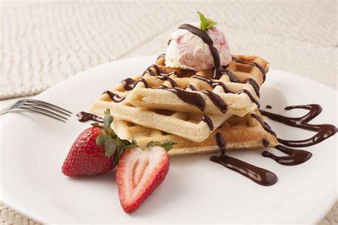 Waffles decorados con fresas frescas, chocolate derretido y una bola de helado de vainilla
