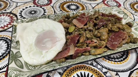Fotografía de un plato de habas fritas con jamón coronadas con un huevo frito recién hecho