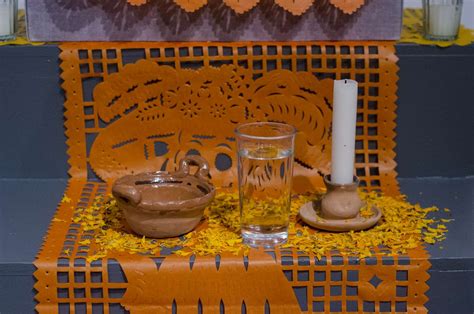 Ofrenda de Día de Muertos con múltiples elementos, destacando el agua y la sal