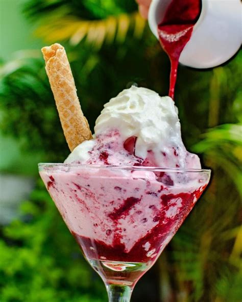 Copa de helado artesanal de pistacho decorada con frutos rojos y sirope