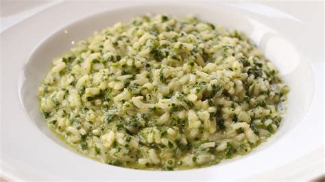 Primer plano de risotto de espinacas y nueces en un plato, mostrando su textura cremosa y las nueces picadas