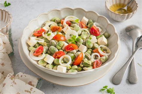 Plato terminado de ensalada de habas con cebolla y limón, presentado de forma apetitosa.