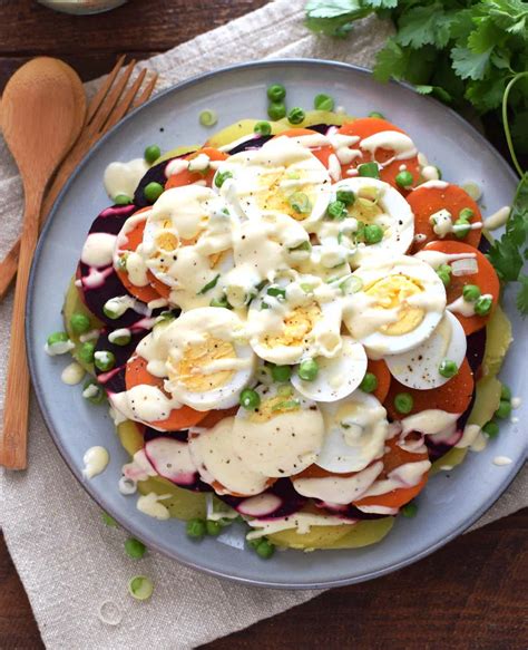 Foto de primer plano de una ensalada fresca con rodajas de palmitos, zanahoria rallada y una cremosa base de mayonesa en un bol elegante.