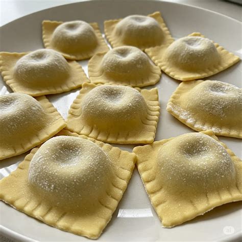 Plato de ravioles de carne con manteca y salvia, decorado con queso rallado