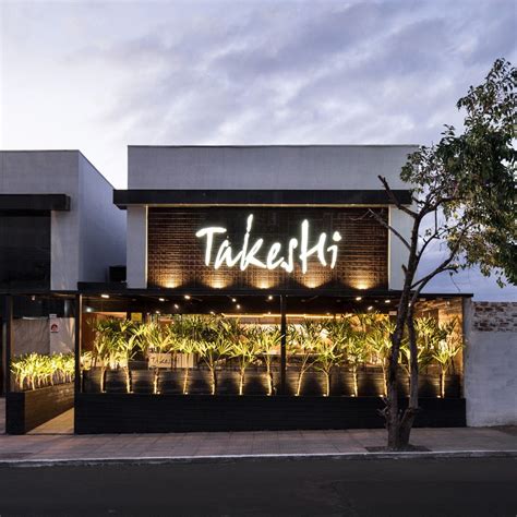 Fachada de restaurante de sushi con gente disfrutando en el interior, en un ambiente moderno y acogedor
