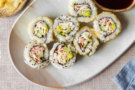 Plato variado de sushi, incluyendo California Rolls y Hot Rolls, con salsas y decoración