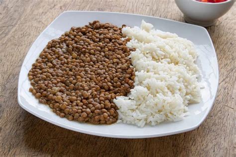 Fotografía de un plato de lentejas con arroz y bacalao, decorado con perejil.