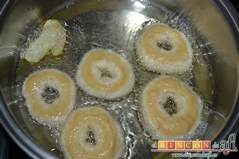 Rosquillas friéndose en aceite caliente con piel de limón