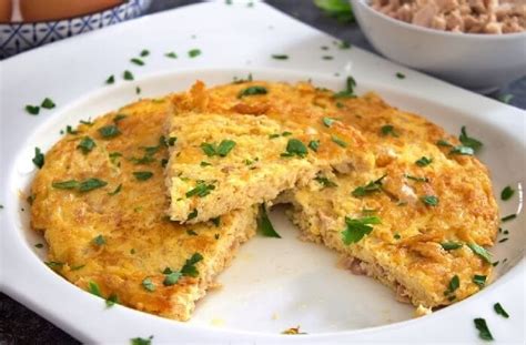 Fotografía de una tortilla de atún dorada servida en un plato, decorada con perejil picado.
