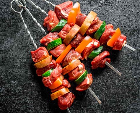 Variedad de brochetas de carne y vegetales asándose en la parrilla