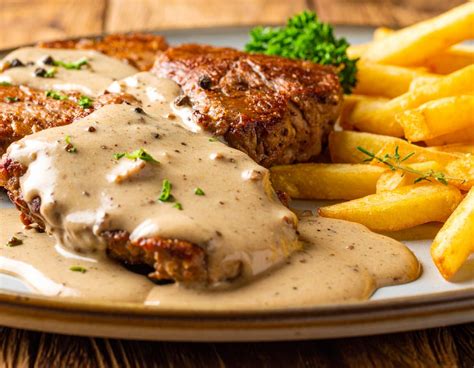Plato servido de medallón de filete a la pimienta con guarnición de puré de papas y especias frescas