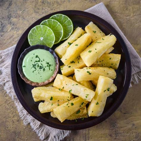 Foto de primer plano de yuca frita dorada y crujiente servida con salsa alioli picante