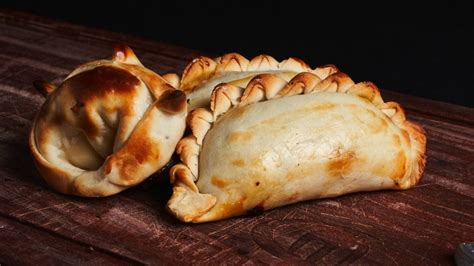 Foto de alta calidad de un conjunto de empanadas caseras recién salidas del horno sobre una tabla de madera.