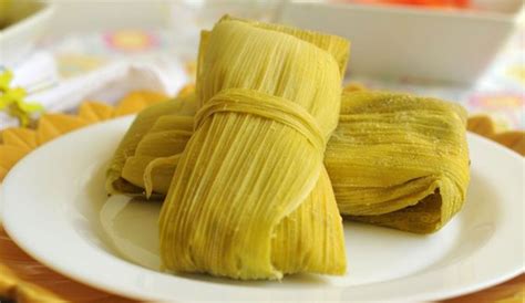 Fotografía de humitas tradicionales recién preparadas envueltas en hojas de choclo.