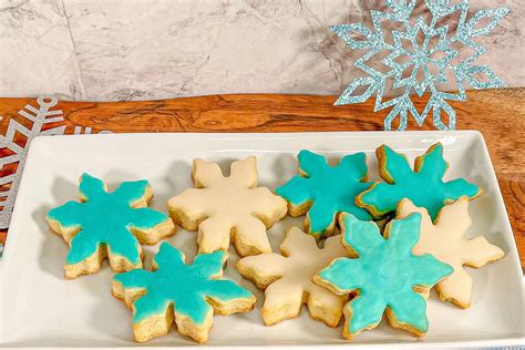 Galletas de mantequilla con forma de copo de nieve, algunas sin decorar y otras con glaseado blanco y azul.
