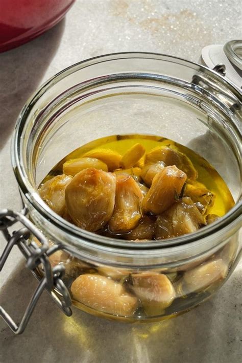 Ajos confitados listos para usar en un tarro de cristal con aceite de oliva.