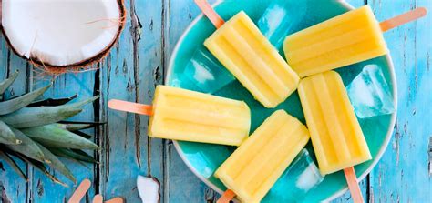 Imagen colorida de paletas de piña colada decoradas con coco rallado y trozos de piña fresca sobre un fondo veraniego