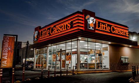 Fotografía de un local de Little Caesars Pizza con su característico branding y letrero iluminado