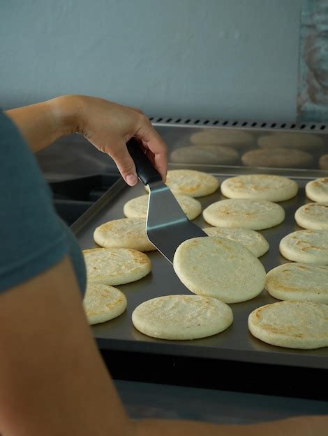 Arepas frescas en una plancha o budare, con algunos quesos cercanos