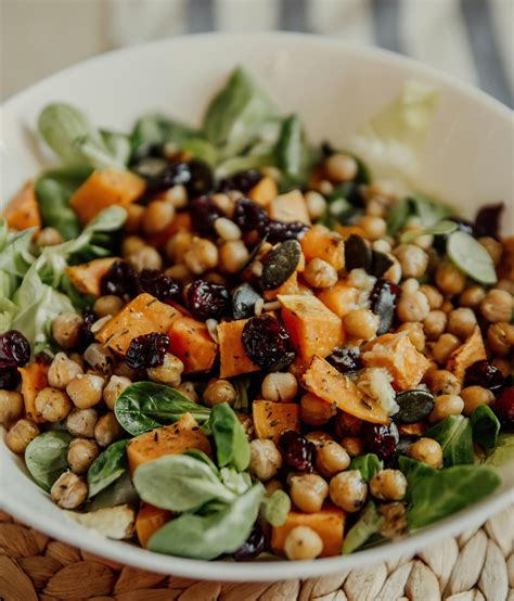 Ensalada de garbanzos con frutas frescas y frutos secos sobre un bol de madera.