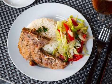 Un plato de arroz con trozos de chuleta, jamón serrano y champiñones, decorado con perejil.