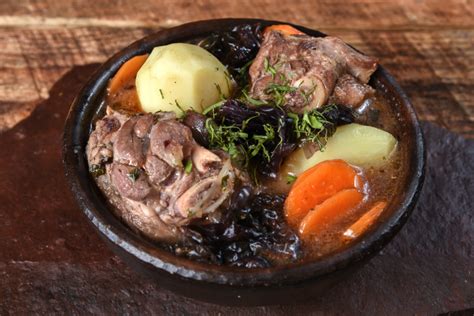 Fotografía gastronómica de una cazuela de cordero servida en una olla de barro tradicional