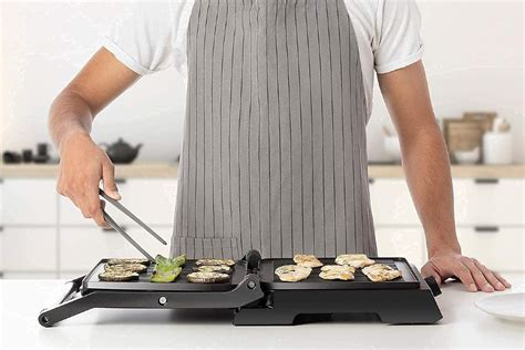 Fotografía de una persona cocinando en una parrilla eléctrica con dimmer en un balcón