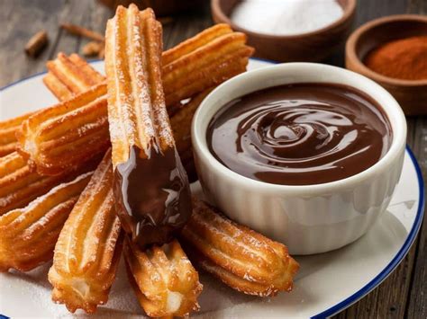 Plato de churros recién hechos acompañados de tazas de chocolate caliente