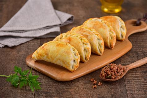 Empanadas veganas de tofu sobre una bandeja de madera con salsa para mojar