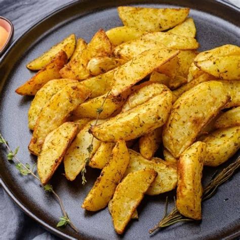 Papas cortadas y aderezadas en una asadera listas para ir al horno.