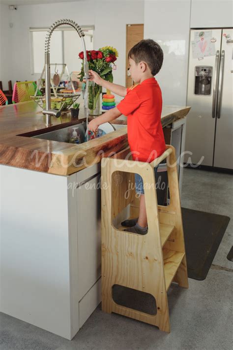 Niño pequeño utilizando una torre de aprendizaje en la cocina