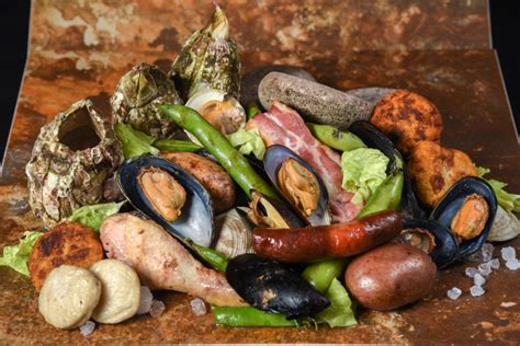 Esquema de un curanto en hoyo con las capas de ingredientes y el método de sellado